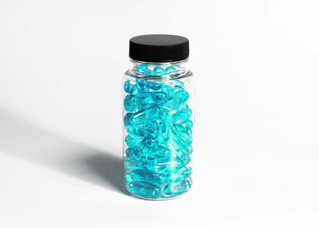 pexels photo 14631439 A clear bottle filled with turquoise capsules, showcasing healthcare and nutrition themes.