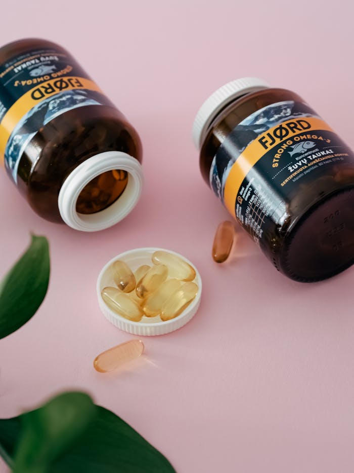 pexels photo 15897788 Close-up of omega 3 supplement bottles and capsules on a pink surface.